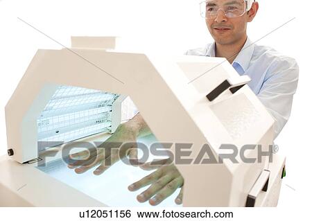 Stock Photograph - Phototherapy booth. Patient with their hands in a phototherapy box.. Fotosearch