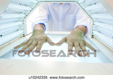 Stock Photography - Phototherapy booth. Patient with their hands in a phototherapy box.. Fotosearch