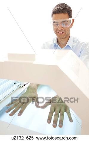 Stock Photography - Phototherapy booth. Patient with their hands in a phototherapy box.. Fotosearch