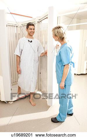 Stock Image - Phototherapy. Dermatologist helping a patient into a phototherapy booth.. Fotosearch