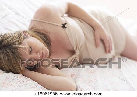 Stock Photograph - Pregnant woman sleeping. She is 35 weeks pregnant.. Fotosearch
