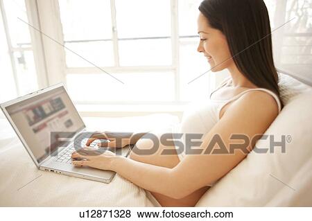Stock Photo - Pregnant woman using a laptop in bed.. Fotosearch