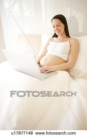Pregnant woman using a laptop in bed. View Large Photo Image Stock Photo - Pregnant woman using a laptop in bed.. Fotosearch