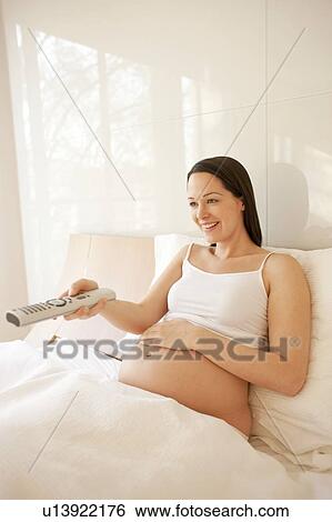 Pregnant woman watching TV in bed. View Large Photo Image Stock Photograph - Pregnant woman watching TV in bed.. Fotosearch