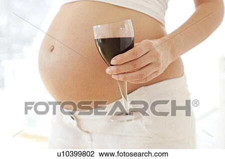 Stock Image - Pregnant woman with a glass of wine.. Fotosearch
