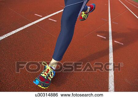 Stock Photograph - Running. Close-up of the legs of a woman running on an athletics track.. Fotosearch