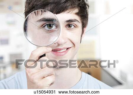 Stock Image - Teenage boy with magnifying glass.. Fotosearch