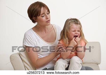 Stock Image - Toddler crying on her mother's lap.. Fotosearch