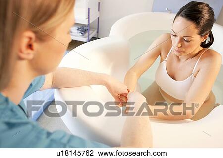 Water birth. Midwife holding the hands of a pregnant woman who is in a birthing pool. View Large Photo Image Stock Image - Water birth. Midwife holding the hands of a pregnant woman who is in a birthing pool.. Fotosearch