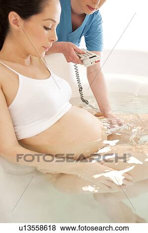 Water birth. Midwife using a doppler monitor to listen to a foetus' heartbeat in a birthing pool. View Large Photo Image Stock Photo - Water birth. Midwife using a doppler monitor to listen to a foetus' heartbeat in a birthing pool.. Fotosearch