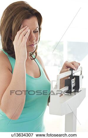 Woman weighing herself. View Large Photo Image Stock Photo - Woman weighing herself.. Fotosearch
