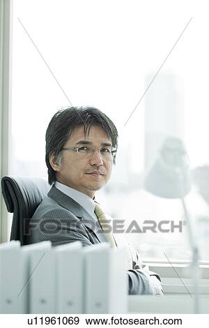 Stock Photo - A businessman holding arms. Fotosearch
