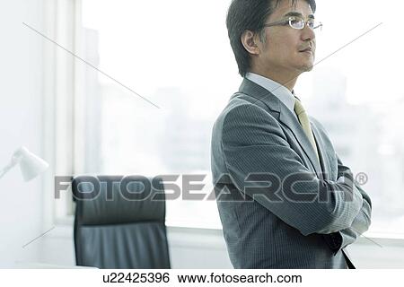 Stock Photograph - A businessman holding arms. Fotosearch