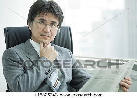 Stock Image - A businessman reading newspapers. Fotosearch