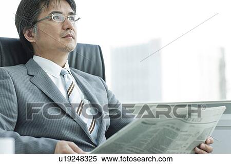 Stock Photography - A businessman reading newspapers. Fotosearch
