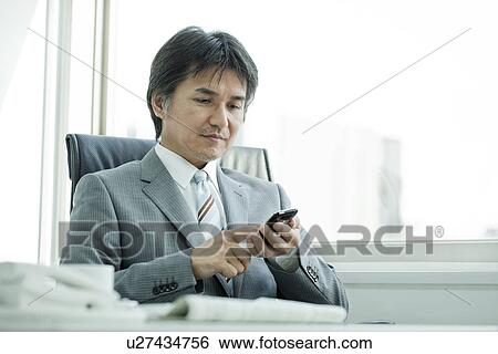 A businessman using a smart phone View Large Photo Image Stock Photograph - A businessman using a smart phone. Fotosearch