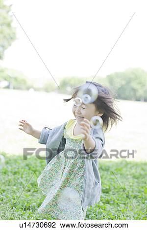 Stock Image - A girl playing bubbles. Fotosearch