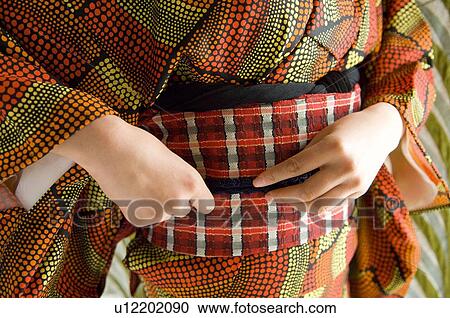 Stock Image - A woman fixing up kimono. Fotosearch