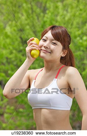 Stock Image - A young woman holding lemons. Fotosearch