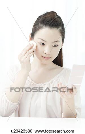 Stock Image - A young woman putting makeup. Fotosearch