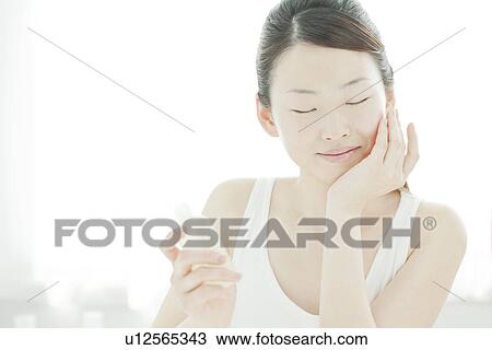 Stock Image - A young woman taking care of face skin. Fotosearch