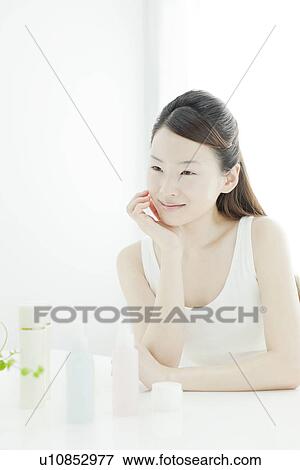 Stock Photo - A young woman taking care of face skin. Fotosearch
