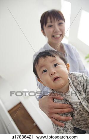 Stock Image - Baby boy and mother in living room. Fotosearch