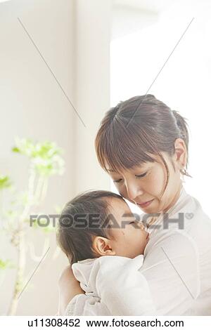 Stock Image - Baby sleeping in mother's arms. Fotosearch