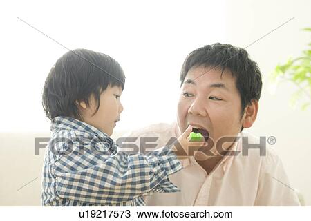 Boy feeding cake to his father View Large Photo Image Stock Image - Boy feeding cake to his father. Fotosearch