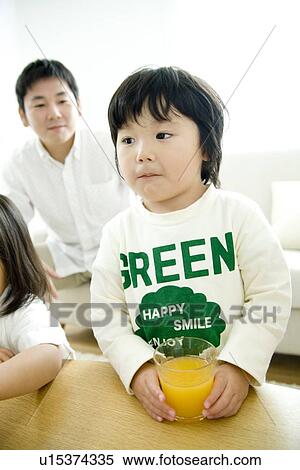 Boy having orange juice, father and sister in background View Large Photo Image Stock Photography - Boy having orange juice, father and sister in background. Fotosearch