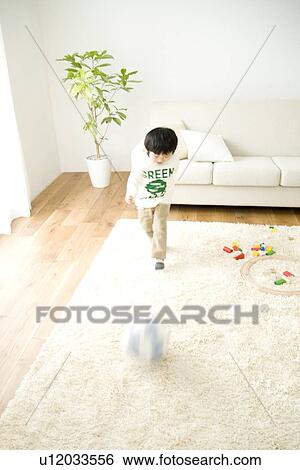 Boy playing with ball in living room View Large Photo Image Stock Photograph - Boy playing with ball in living room. Fotosearch