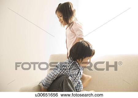 Brother and sister playing in living room View Large Photo Image Stock Photograph - Brother and sister playing in living room. Fotosearch