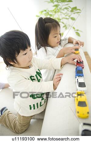 Stock Image - Brother and sister playing with toy cars. Fotosearch