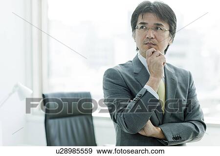 Stock Photo - Businessman Sat On Desk, Thinking. Fotosearch