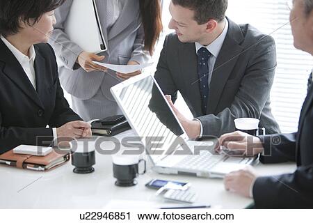 Stock Image - Businessmen and Women In a Meeting. Fotosearch