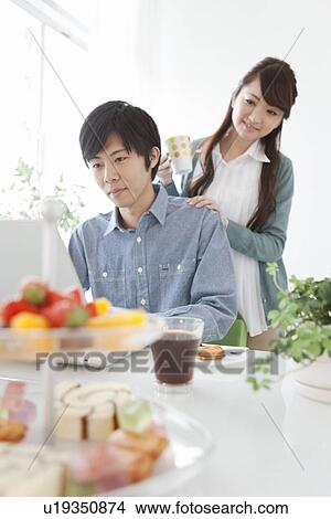 Picture - Dining Table, Couple Using Laptop In Background. Fotosearch