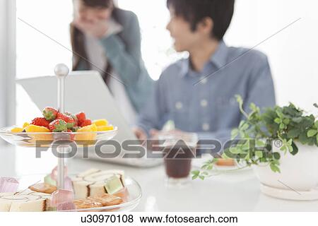 Stock Photo - Dining Table, Couple Using Laptop In Background. Fotosearch