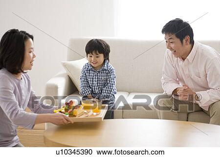 Family eating cake in living room View Large Photo Image Stock Image - Family eating cake in living room. Fotosearch