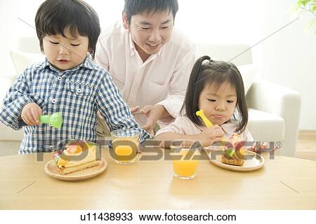 Family eating cake in living room View Large Photo Image Stock Image - Family eating cake in living room. Fotosearch