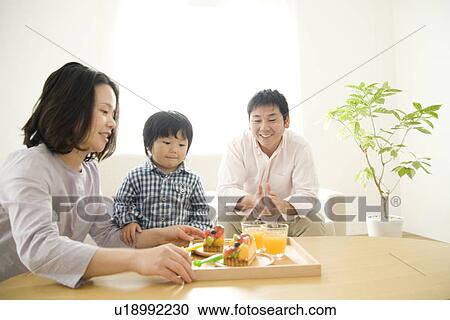 Family eating cake in living room View Large Photo Image Stock Image - Family eating cake in living room. Fotosearch
