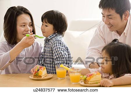 Family eating cake in living room View Large Photo Image Stock Photo - Family eating cake in living room. Fotosearch