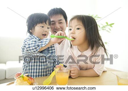 Stock Photograph - Family eating cake in living room. Fotosearch