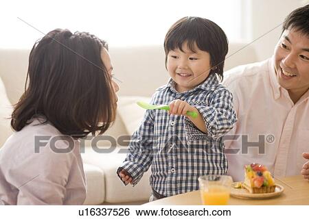 Family eating cake in living room View Large Photo Image Stock Photograph - Family eating cake in living room. Fotosearch