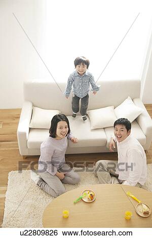 Family having cake, boy jumping on sofa View Large Photo Image Stock Photograph - Family having cake, boy jumping on sofa. Fotosearch