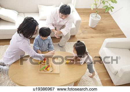 Stock Photo - Family having food in living room. Fotosearch