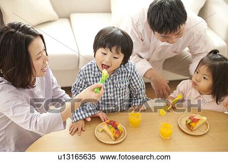 Family having food in living room View Large Photo Image Stock Photography - Family having food in living room. Fotosearch