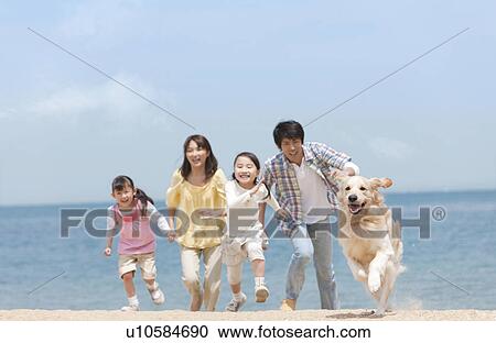 Stock Image - Family of Four and Dog Running on Beach. Fotosearch