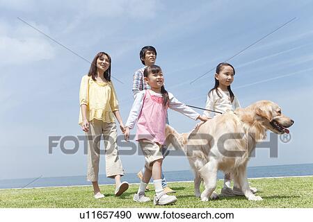 Stock Image - Family of Four and Dog Walking on Beach. Fotosearch