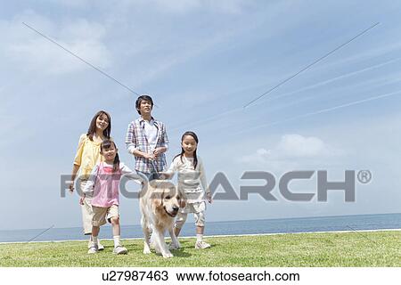 Stock Image - Family of Four and Dog Walking on Beach. Fotosearch