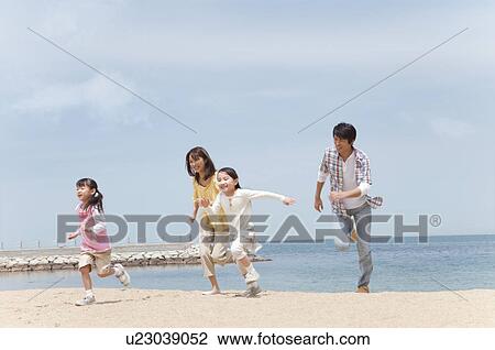 Stock Image - Family of Four Running on Beach. Fotosearch